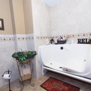 A cozy bathroom featuring a large bathtub with surrounding decor.