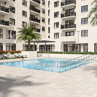 A modern residential complex with a swimming pool surrounded by palm trees.