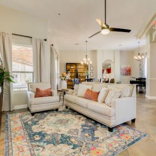 A cozy and stylish living room featuring a comfortable sofa, an armchair, and a decorative rug, illuminated by natural light.