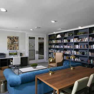 A modern living room and home office with extensive bookshelves and stylish furniture.