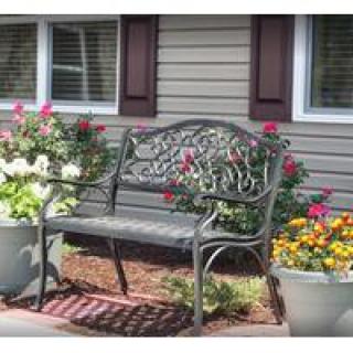 A decorative bench surrounded by colorful potted flowers in a garden setting.