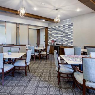A modern dining area with neatly arranged tables and chairs, featuring stylish ceiling lights and contemporary decor.