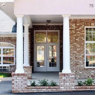 Front entrance of a brick building with columns and double doors.