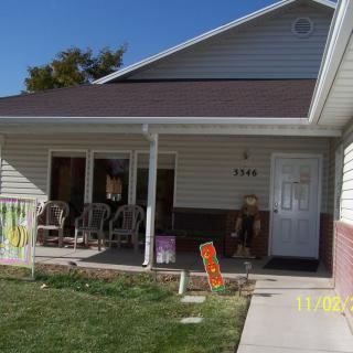 A suburban house with a front porch and well-maintained lawn on a sunny day.