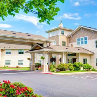 A well-maintained residential building with a landscaped entrance and a clear sky overhead.