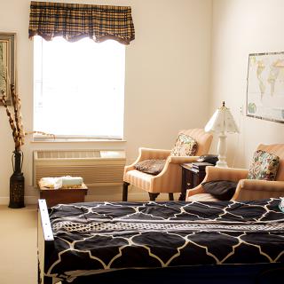Cozy bedroom with a stylish bed, armchairs, and a large window.