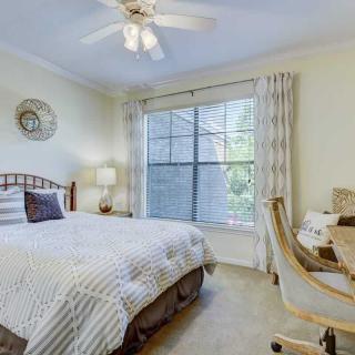 A cozy bedroom with a neatly made bed, a desk by the window, and tasteful decor.