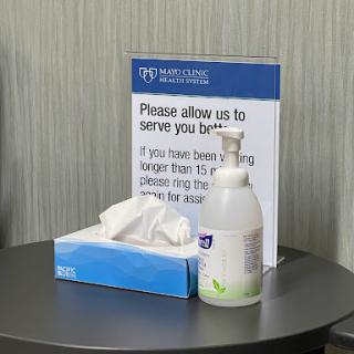 A customer service sign alongside hand sanitizer and tissues in a waiting area.