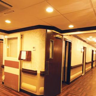 A view of a well-lit hospital corridor with doors on either side.