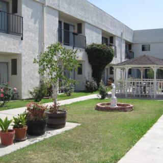 A well-maintained apartment complex courtyard featuring a gazebo, greenery, and a pathway.