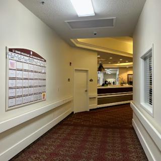A well-lit hallway featuring a calendar on the wall, leading towards a reception area.