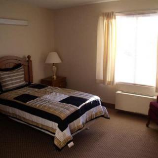 A cozy bedroom with a single bed, bedside lamp, and window with curtains.