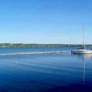 A peaceful scene with a sailboat on a calm lake under a clear blue sky.