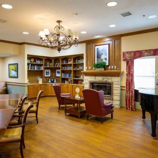 A cozy living room with a fireplace, bookshelves, and a chandelier.