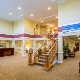 A spacious lobby area with a grand staircase and warm lighting.