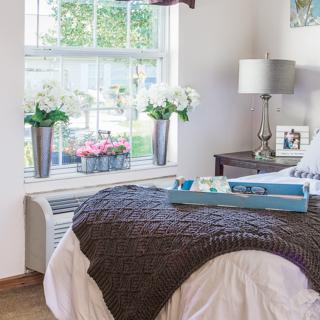 A cozy bedroom with fresh flowers and a neatly arranged bed.