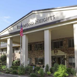 Entrance of a building with columns, featuring an American flag and landscaping.
