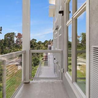 Modern apartment balcony with a glass railing overlooking a scenic view.