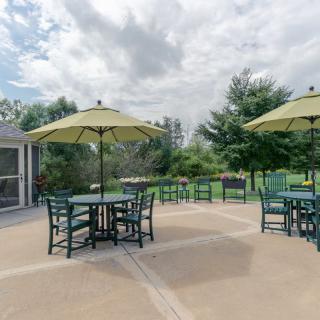 A serene outdoor patio area with tables, chairs, and umbrellas surrounded by greenery.