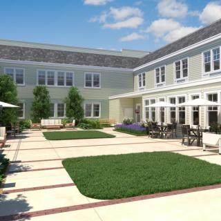 A serene courtyard surrounded by a modern building under a clear blue sky.