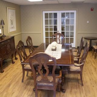 A classic dining room setting with a wooden table and chairs on a polished hardwood floor.