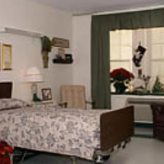 A cozy hospital room with a single bed, decorated with poinsettias and holiday decor near the window.