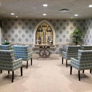 A serene waiting area with patterned chairs and decorative elements, including plants and a central table.