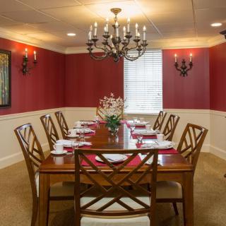 Elegant dining room with a large wooden table, chandelier, and red wall accents.