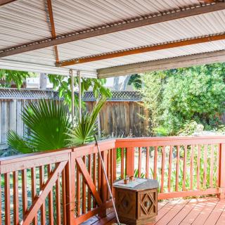 A wooden deck with a covered roof overlooking a garden with lush greenery.