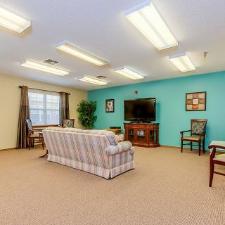A cozy living room with a sofa, television, and various seating arrangements.