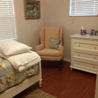 A cozy bedroom with a bed, armchair, and dresser.