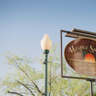 A beautifully lit sign for 'Hospice Springs' against a clear blue sky.