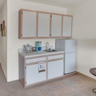 A small kitchen area featuring a sink, upper and lower cabinets, and a refrigerator.