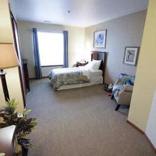 A cozy bedroom with a single bed, a window with curtains, and comfortable furnishings.
