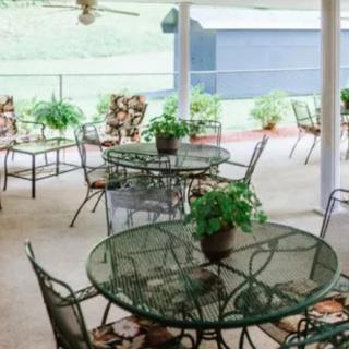 A cozy outdoor patio with metal tables and chairs, adorned with potted plants.