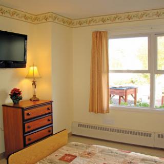 A cozy bedroom with a window, TV, and dresser.