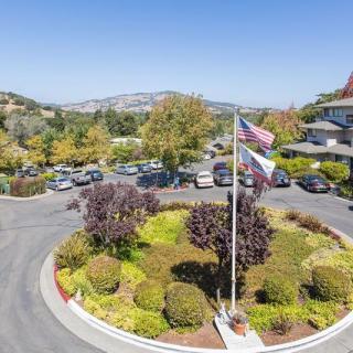 A roundabout with flags at the entrance of a parking lot surrounded by trees and hills.