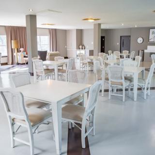A modern and spacious dining area with white tables and chairs.