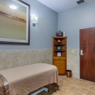 A serene spa room with a massage table, wooden cabinet, and calming decor.