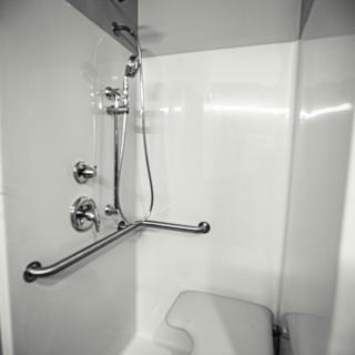 A modern, accessible shower with a grab bar in a white bathroom.