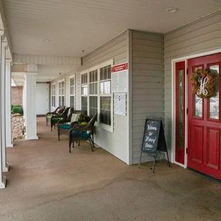 A welcoming porch with chairs and a festive red door.
