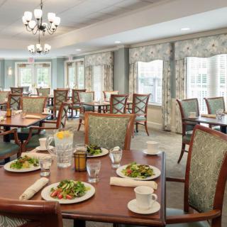 A well-furnished dining area with tables set for meals, featuring elegant decor and natural light.