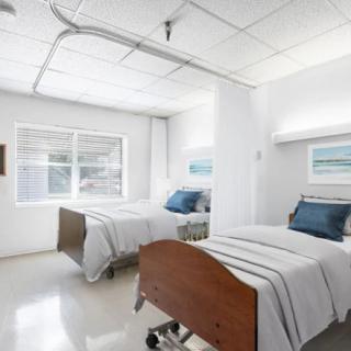 A clean and well-lit hospital room with two beds and medical equipment.
