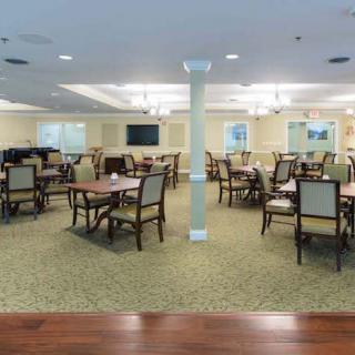 A spacious dining room with multiple tables and chairs, well-lit and designed for gatherings.