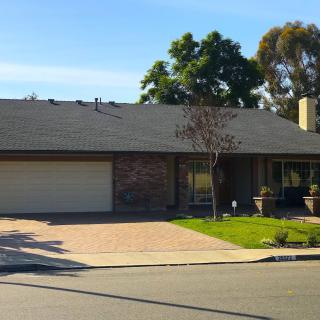 A suburban house with a driveway and garage, surrounded by a well-maintained lawn.