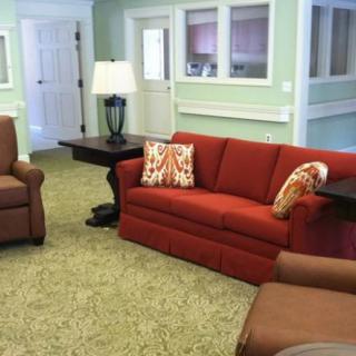A cozy living room with a red sofa, armchairs, and a lamp on a side table.