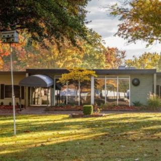 A mid-century modern house surrounded by autumn foliage.