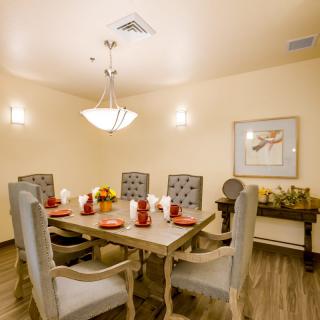 A beautifully set dining room with elegant chairs and a chandelier.