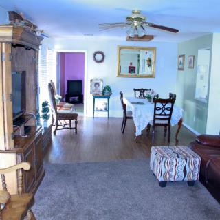 A cozy living and dining area with a television, dining table, and ceiling fan.