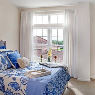 A cozy bedroom with blue and white decor, featuring a large window that lets in ample natural light.